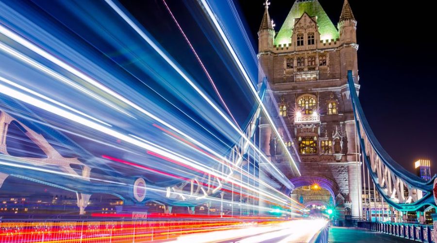 A photo capturing a light trail with leading lines leading to a cityscape in the background